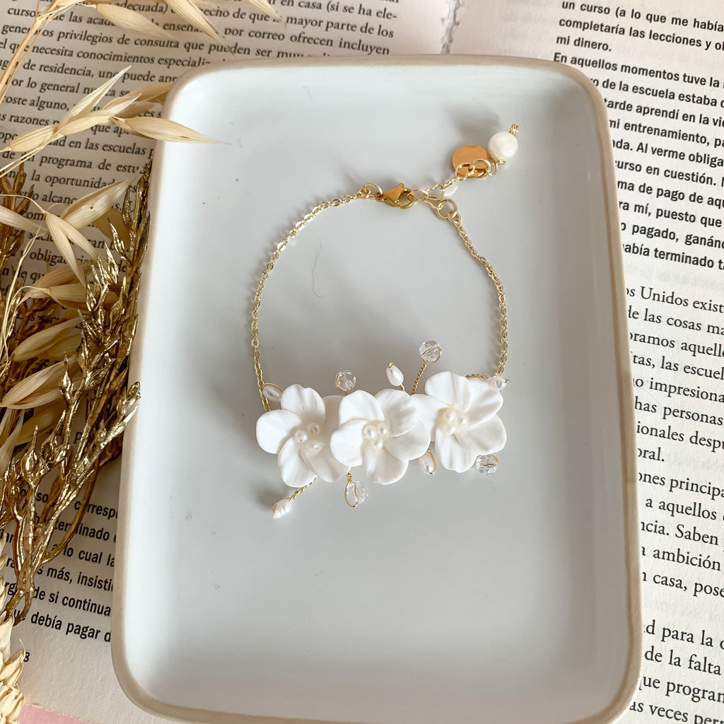A handcrafted bridal bracelet featuring delicate polymer clay flowers paired with elegant pearls. The lifelike floral design and lustrous pearls create a romantic and timeless look, perfect for adding a unique, artisanal touch to a bride’s wedding ensemble. Ideal for brides seeking a blend of elegance and handmade charm.
