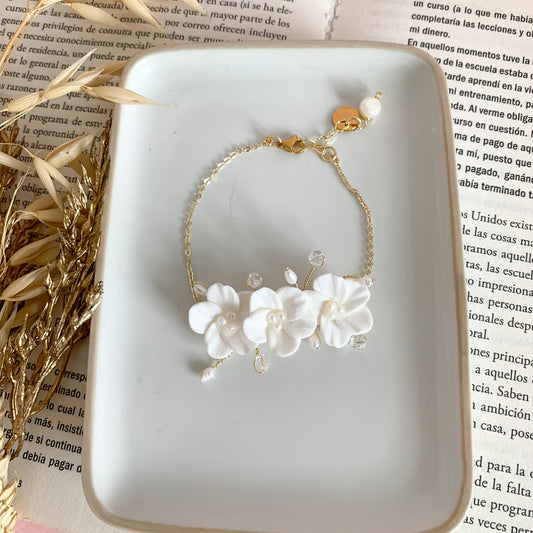 A handcrafted bridal bracelet featuring delicate polymer clay flowers paired with elegant pearls. The lifelike floral design and lustrous pearls create a romantic and timeless look, perfect for adding a unique, artisanal touch to a bride’s wedding ensemble. Ideal for brides seeking a blend of elegance and handmade charm.