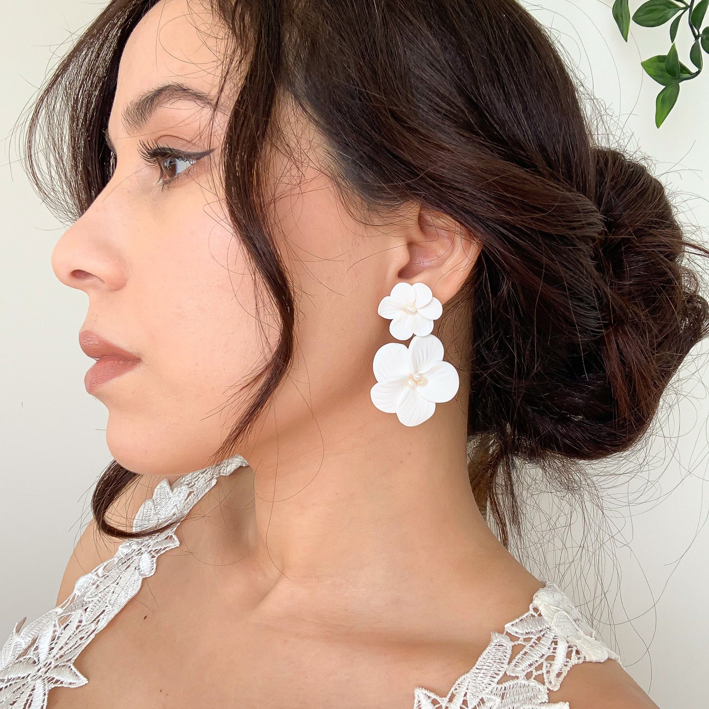 Woman wearing white floral earrings with a white lace dress