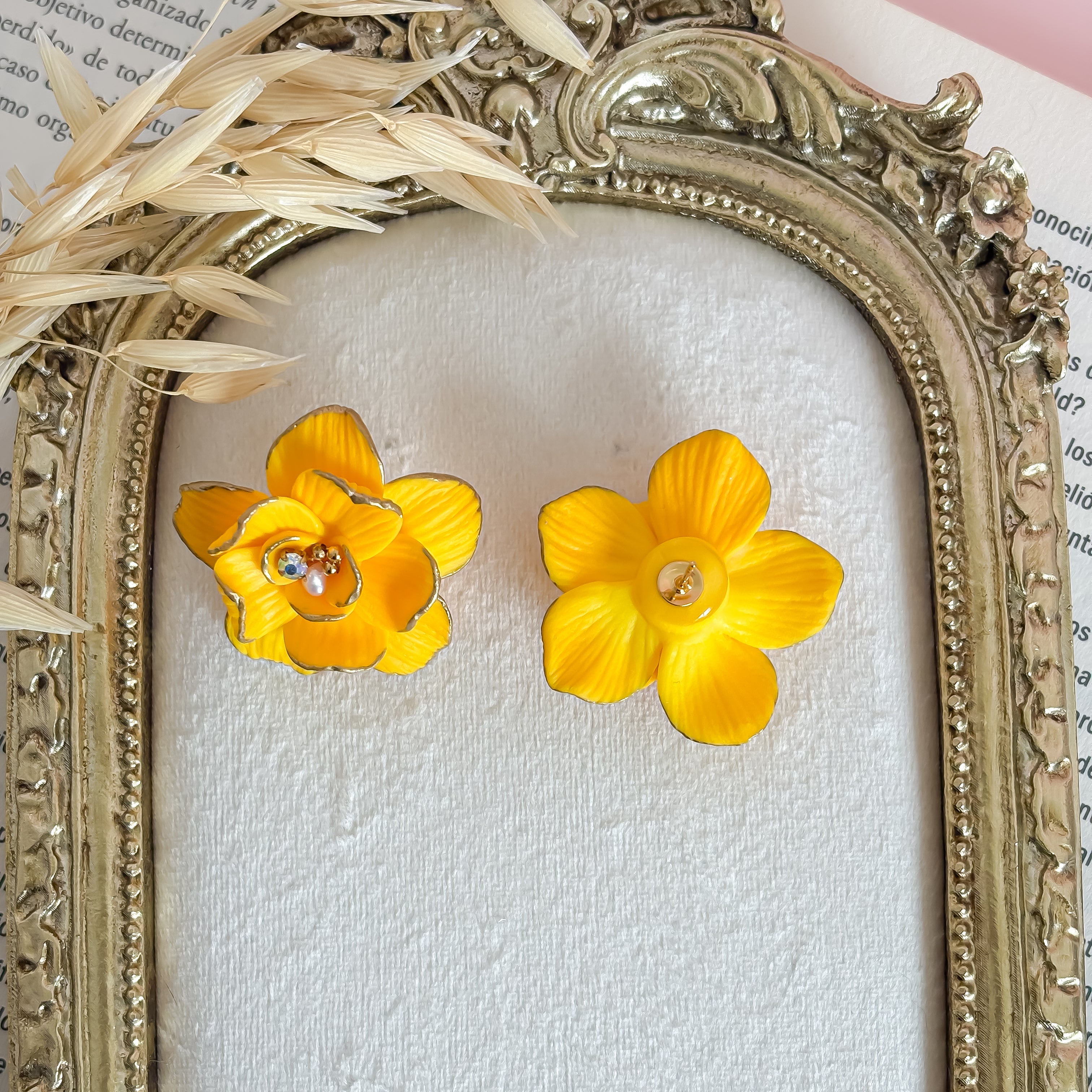 Yellow flower earrings displayed in an ornate frame.