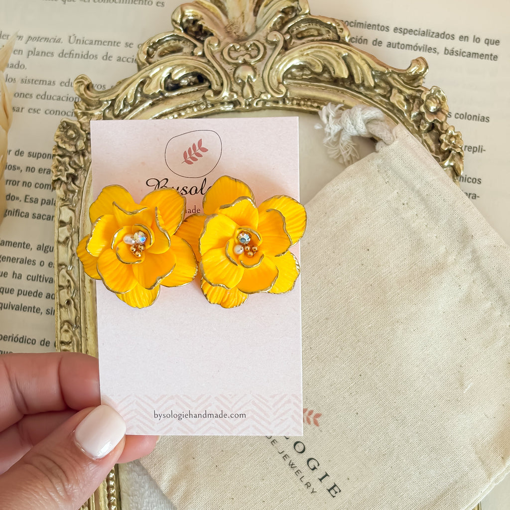 Yellow flower earrings on a card with a gold frame and pink background