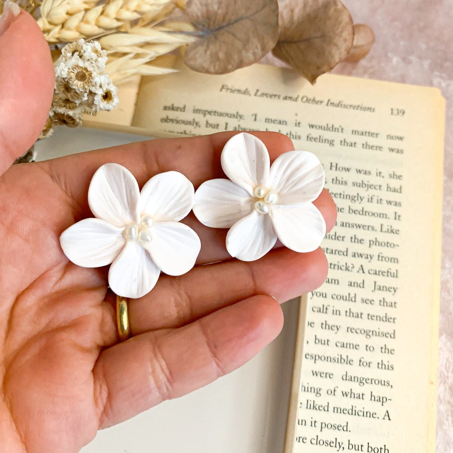 sample measurement of white floral earrings using the hand as reference