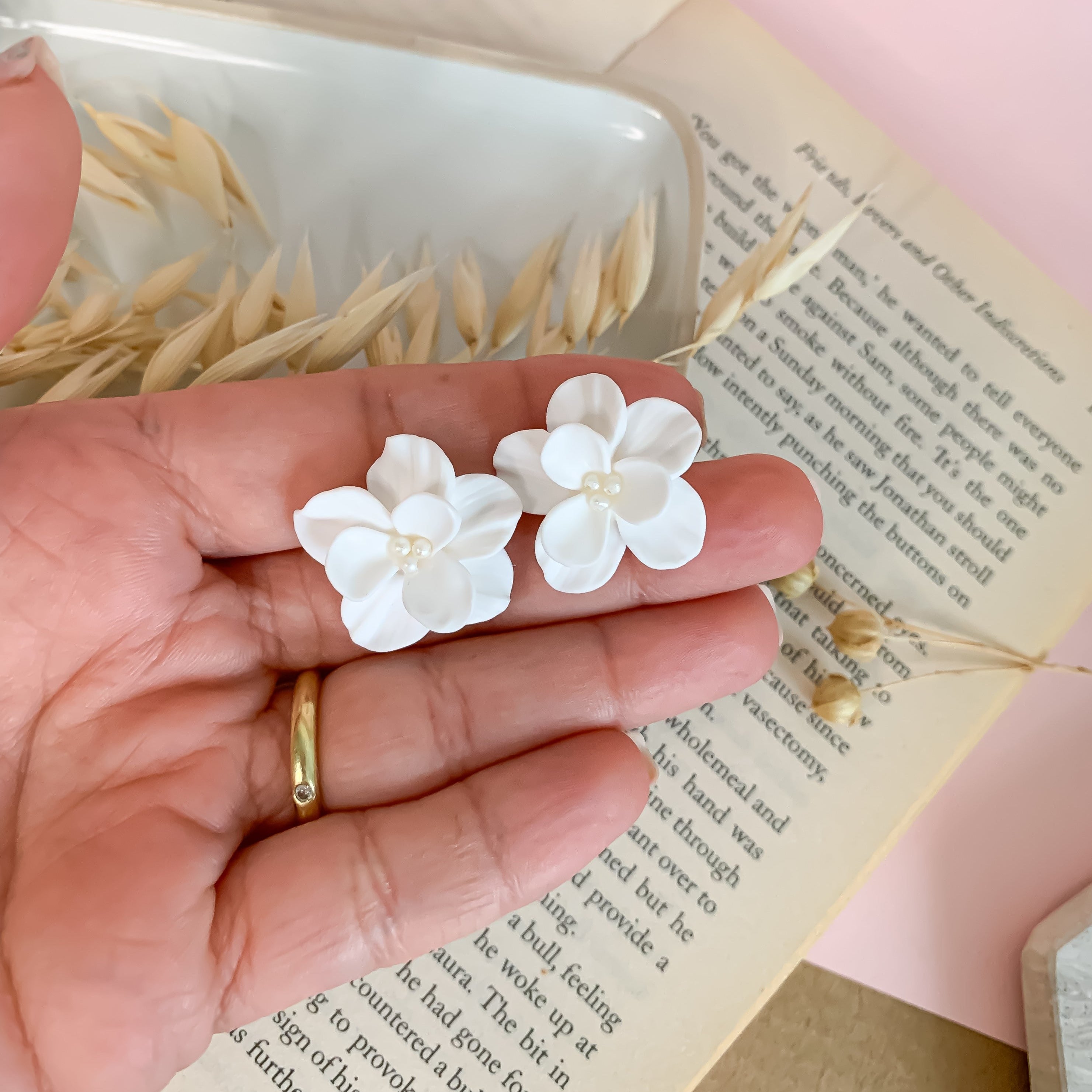 white flower earrings measured by the hand