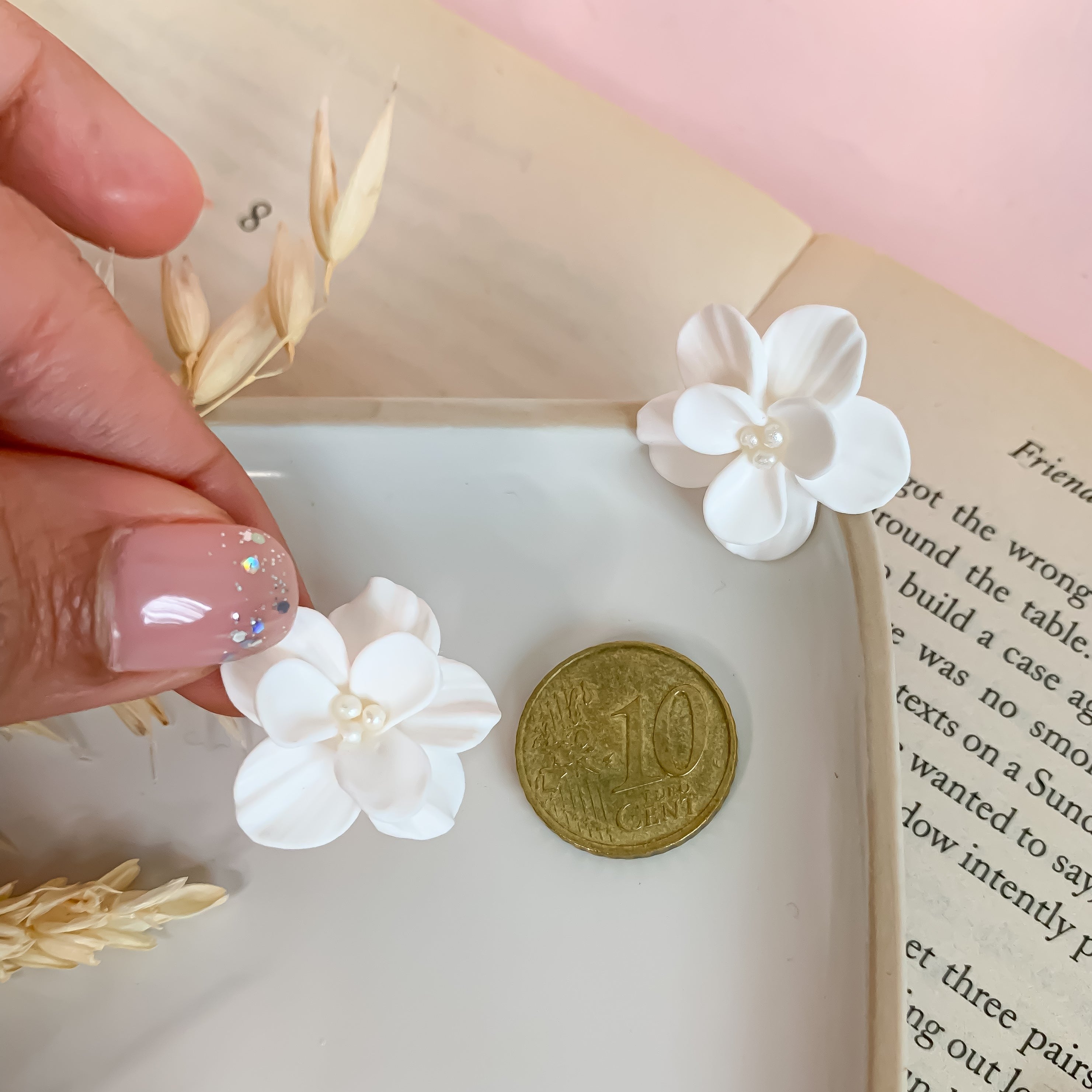 white flower earrings taking as a reference measure 10 euro cent coin