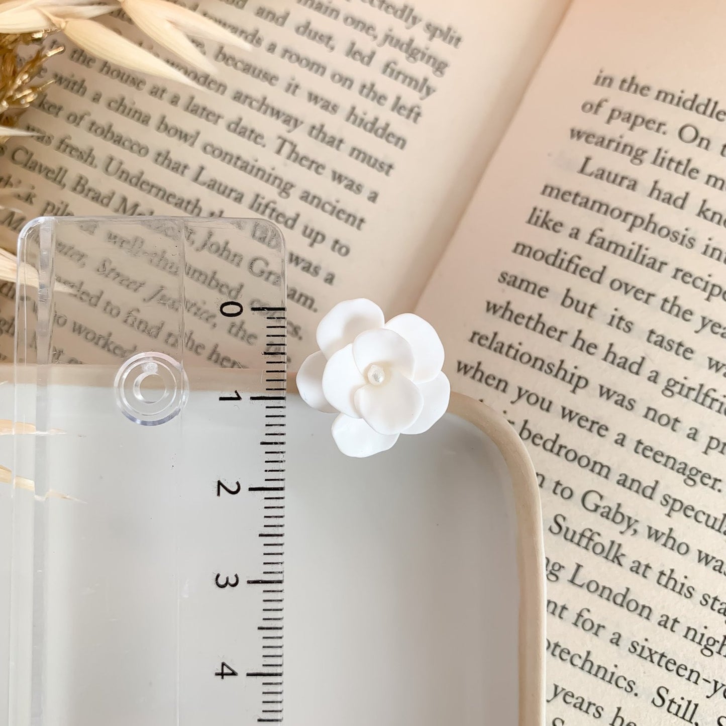 Kleine witte bloem oorbellen gemeten met een liniaal