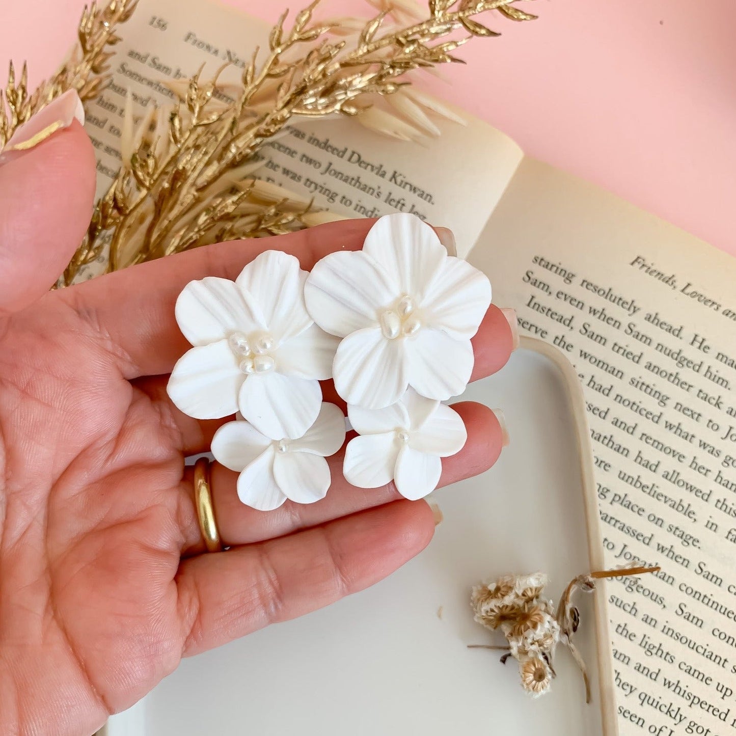 Double white flower earrings measuring them by hand 