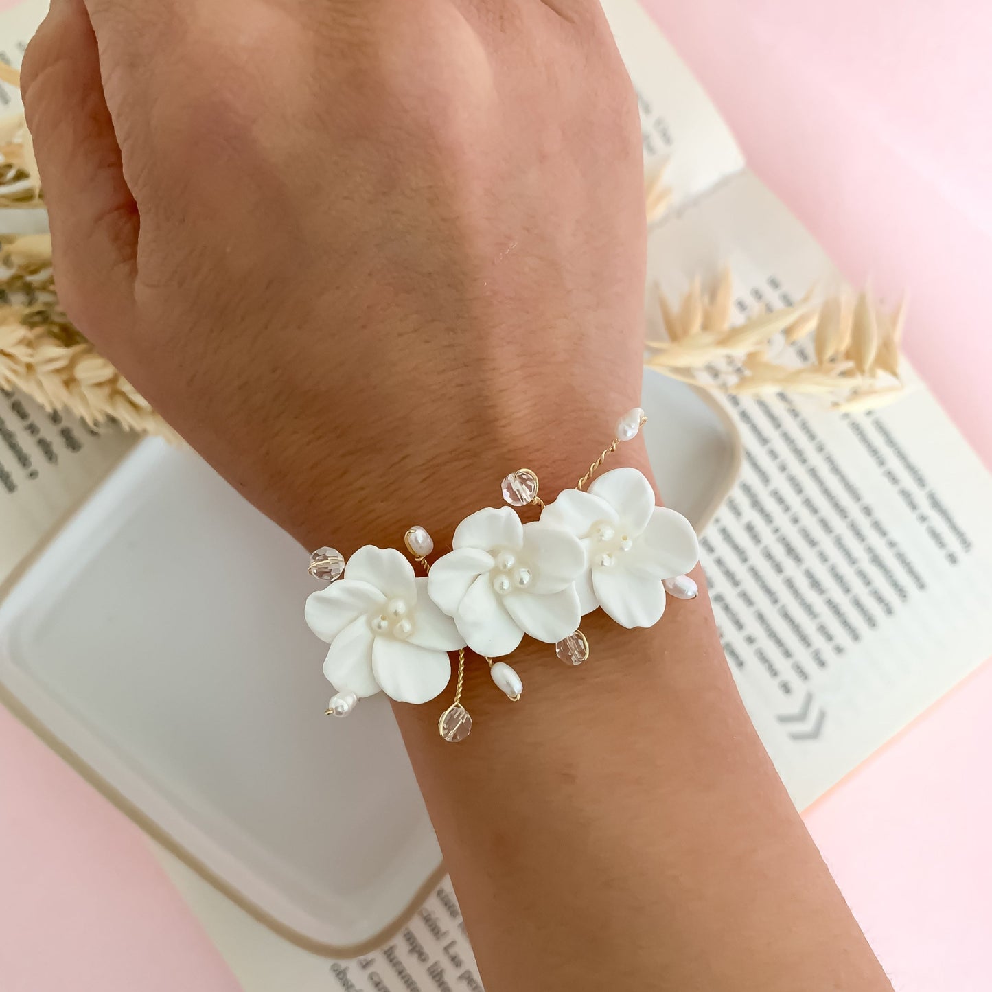 A handcrafted bridal bracelet featuring delicate polymer clay flowers paired with elegant pearls. The lifelike floral design and lustrous pearls create a romantic and timeless look, perfect for adding a unique, artisanal touch to a bride’s wedding ensemble. Ideal for brides seeking a blend of elegance and handmade charm.